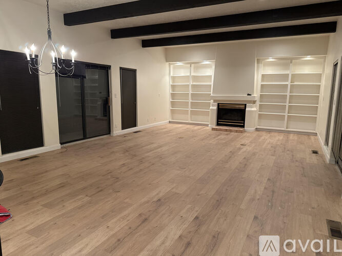 A spacious room with wooden flooring and a fireplace.