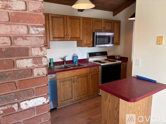 A kitchen with wooden cabinets and a brick wall.