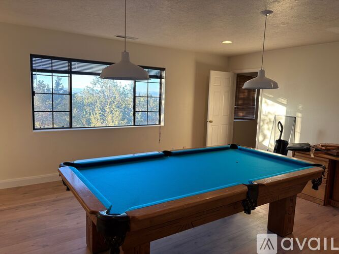 A pool table in a room with a window.