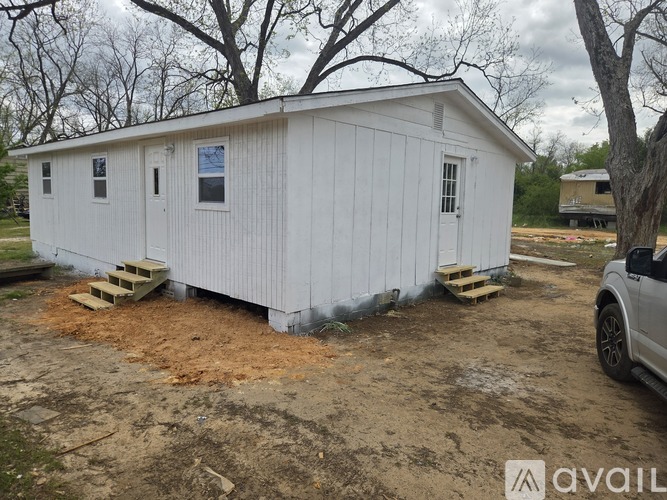 A white shed with a brown roof is situated in a yard.
