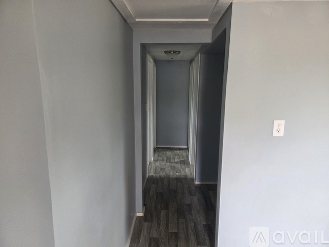 A hallway with a wooden floor and a door at the end.