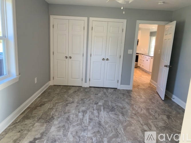 A room with two white doors and a kitchen visible through the open door.
