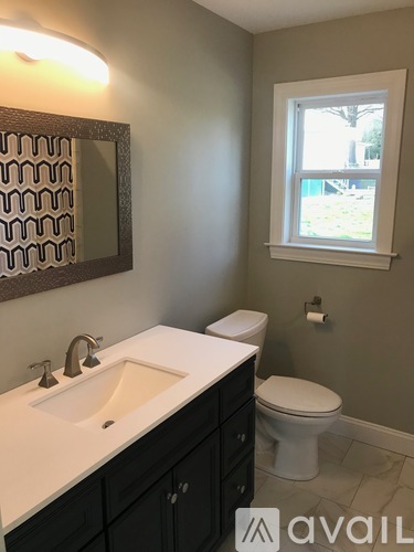 A bathroom with a sink, toilet and window.