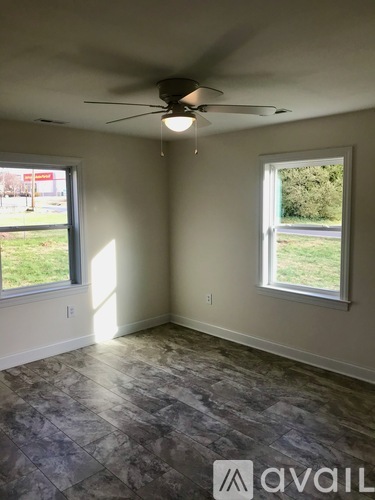 A room with a ceiling fan and two windows.