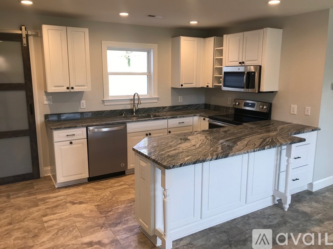 A kitchen with white cabinets and a granite countertop.