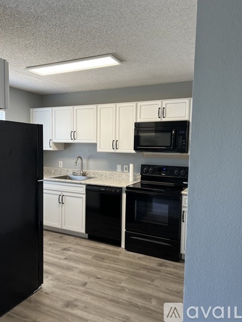 A kitchen with black appliances and white cabinets.