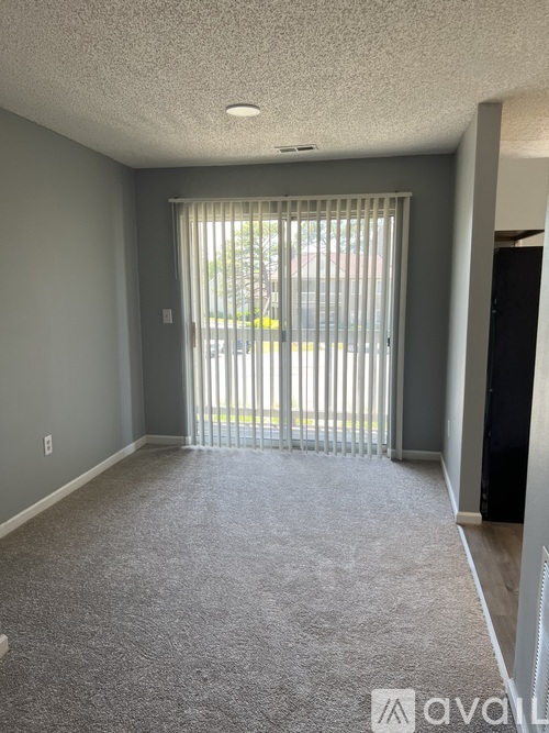 A room with a carpeted floor and a sliding glass door.
