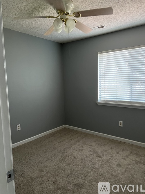 A room with a ceiling fan and a window with blinds.