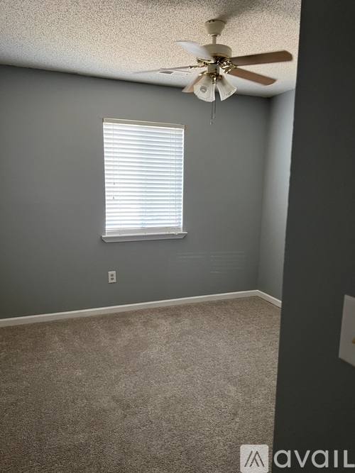 A room with a ceiling fan and a window with blinds.