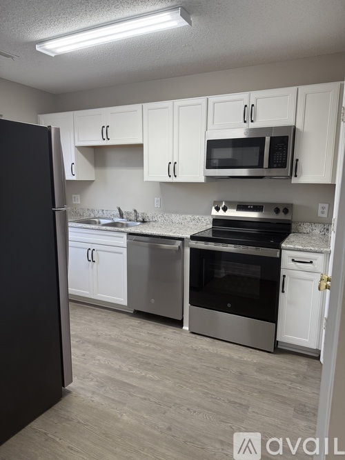 A kitchen with white cabinets and a black refrigerator.