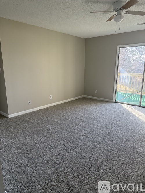 A room with a carpeted floor and a ceiling fan.