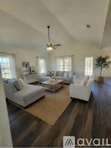 A living room with white furniture and a ceiling fan.