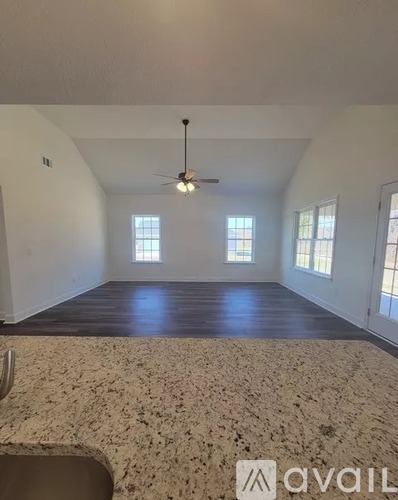A spacious room with a ceiling fan and two windows.