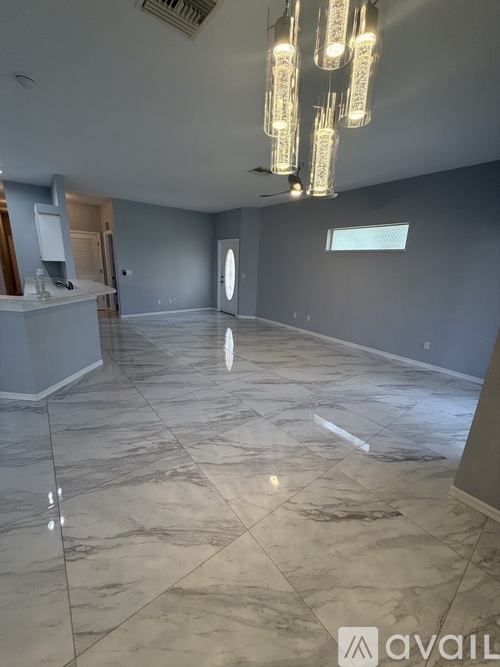 A spacious room with marble flooring and a chandelier.
