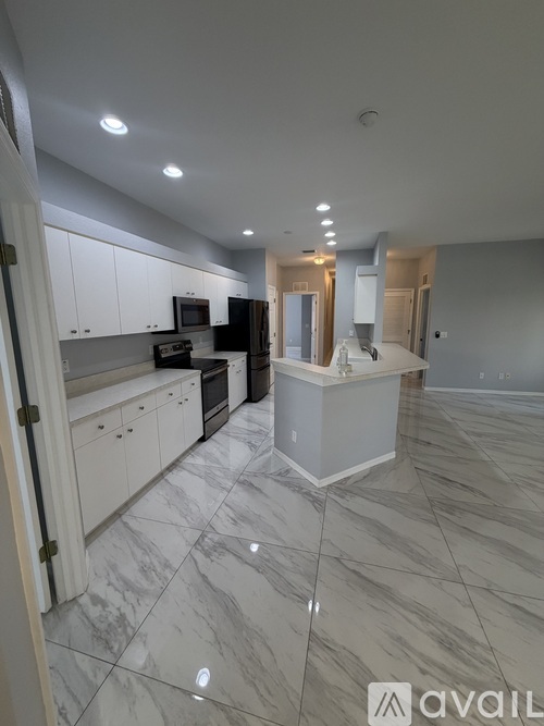 A kitchen with white cabinets and marble flooring.