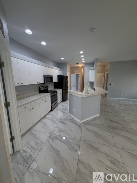 A kitchen with white cabinets and marble flooring.