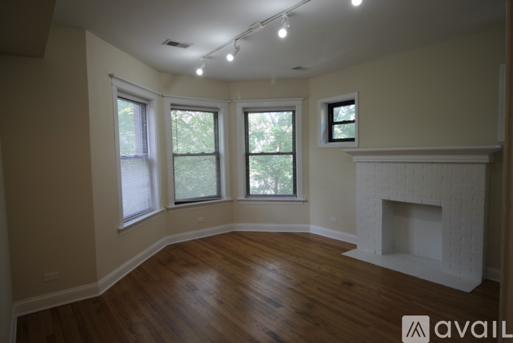 A living room with a fireplace and three windows.