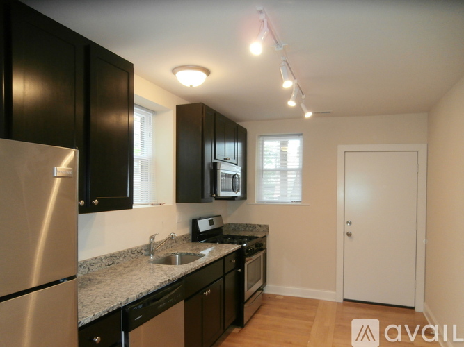 A kitchen with black cabinets and a stainless steel refrigerator.