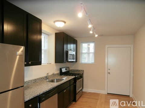 A kitchen with black cabinets and a stainless steel refrigerator.