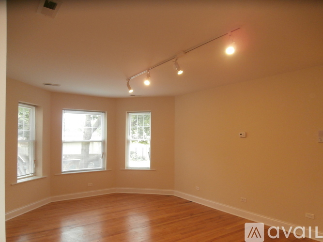 A room with wooden floors and three windows.
