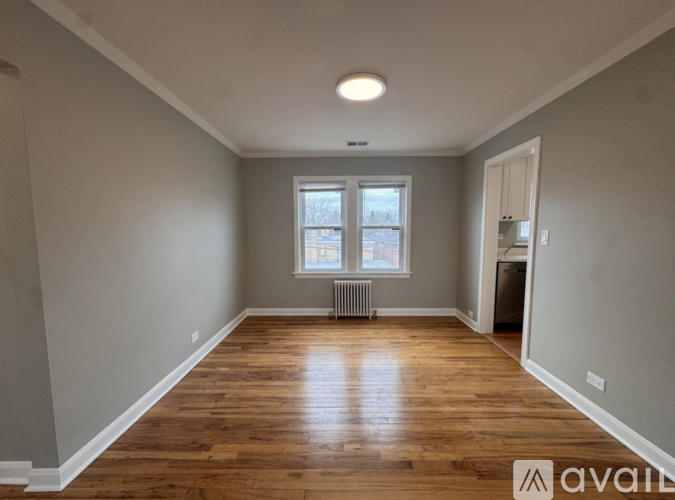 A room with wooden floors and a window with a view of a building outside.