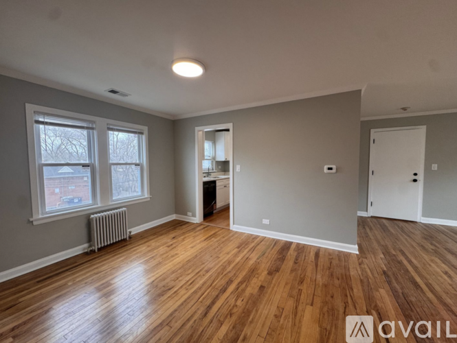 A room with wooden floors and a window showing a view of a building outside.