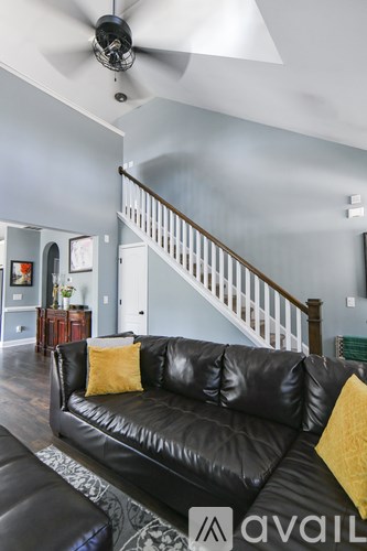 A living room with a black leather couch and a ceiling fan.