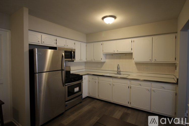 A kitchen with white cabinets and a stainless steel refrigerator.