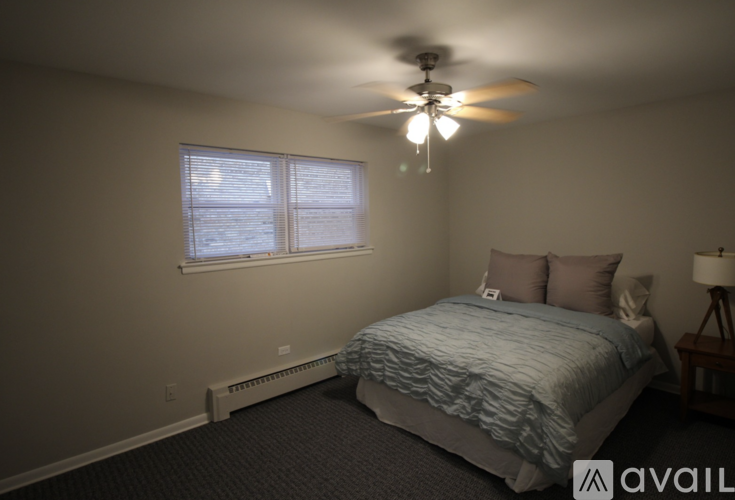 A bedroom with a bed, ceiling fan, and window.