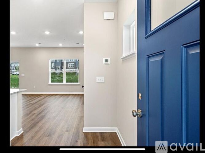 A room with a blue door and a window overlooking a street.