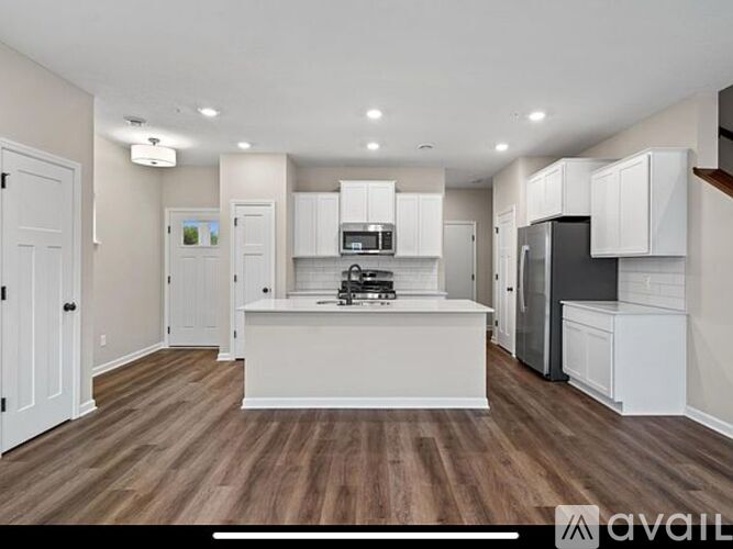 A kitchen with white cabinets and a wooden floor.