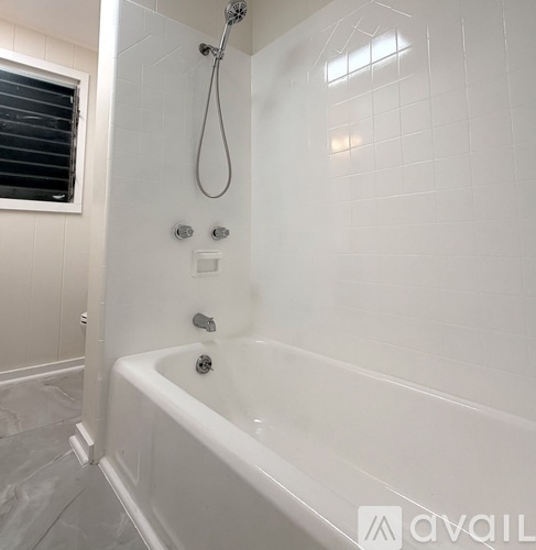 A white bathtub with a shower head and controls.