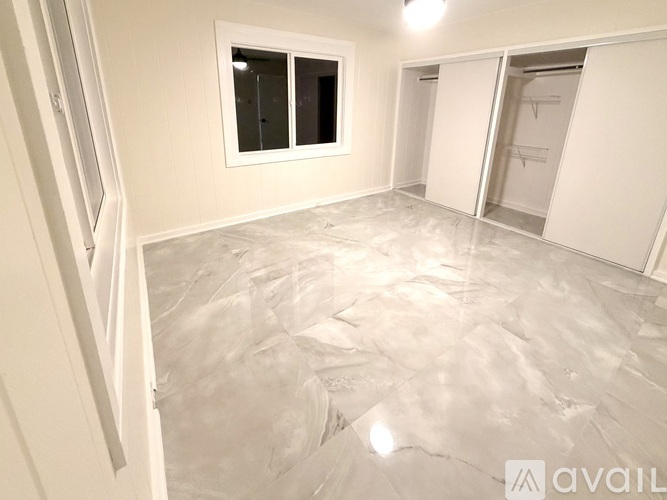 A spacious room with marble flooring and white cabinetry is available.