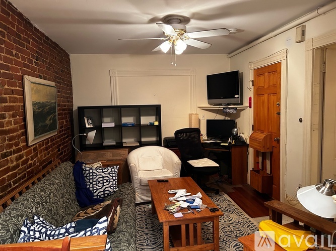 A living room with a brick wall and a ceiling fan.
