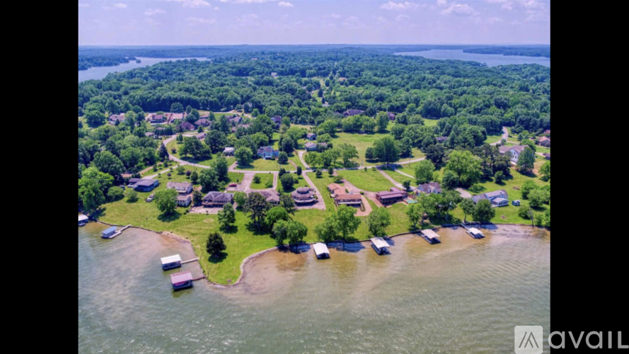 A bird's eye view of a residential area with houses, trees, and a body of water.