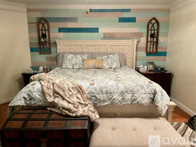 A bedroom with a bed, a trunk, and two mirrors.