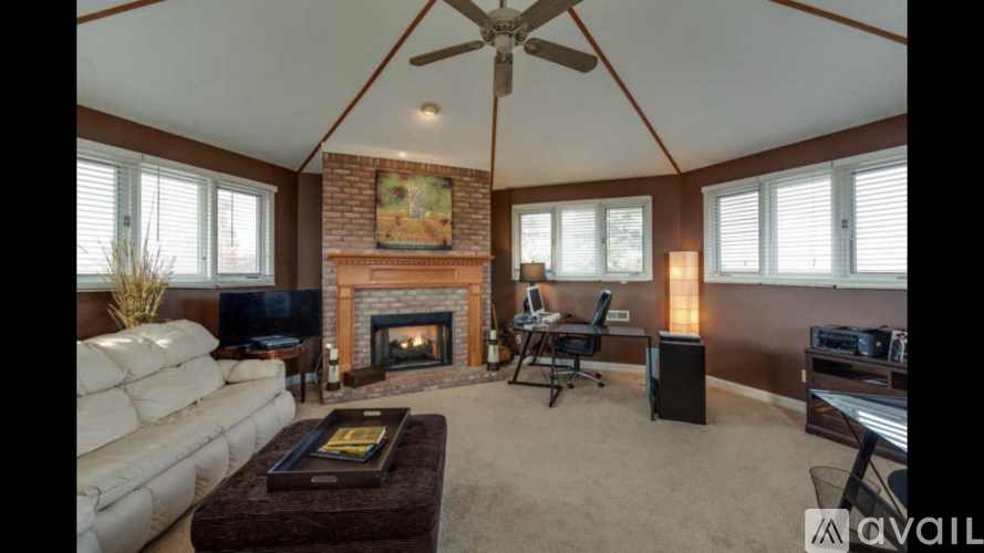 A living room with a fireplace and a ceiling fan.