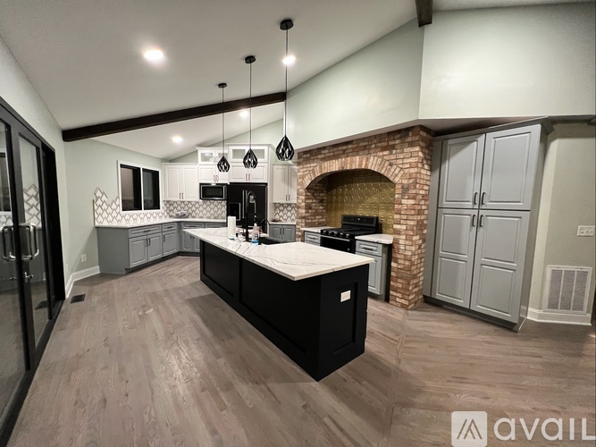 A modern kitchen with a brick fireplace and a large island.