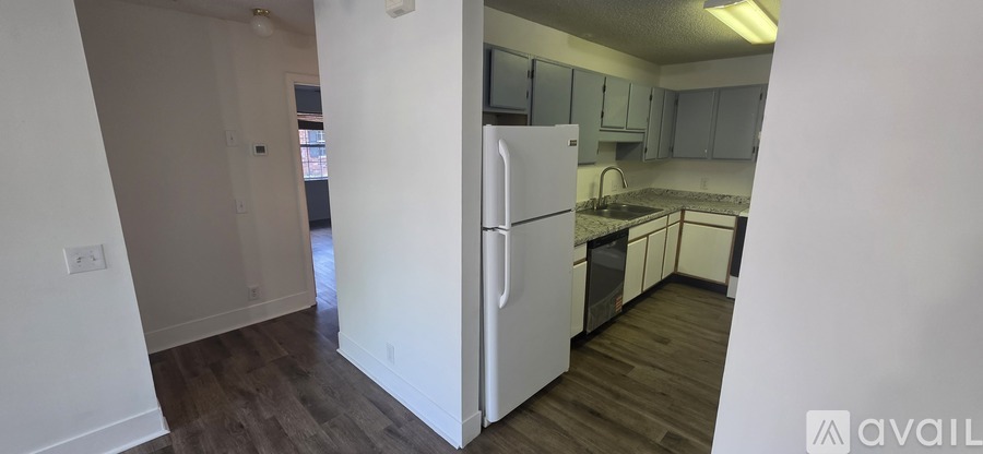 A kitchen with white appliances and wooden floors.