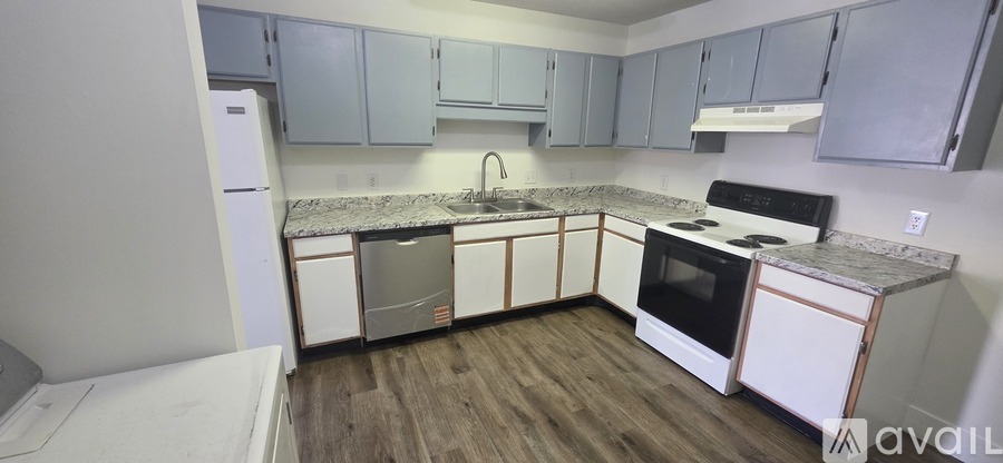 A kitchen with white appliances and wooden floors.