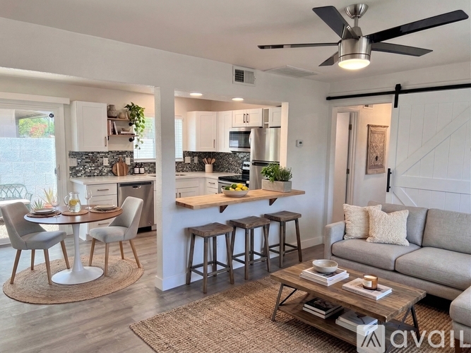 A modern living room with a dining area and kitchen in the background.