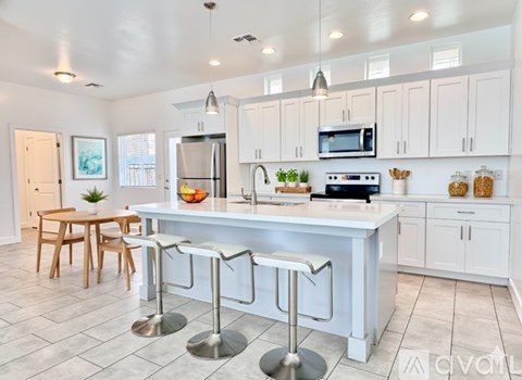 A kitchen with white cabinets and a central island with bar stools.