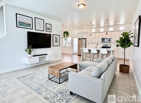A living room with a grey couch, a coffee table, and a television on the wall.