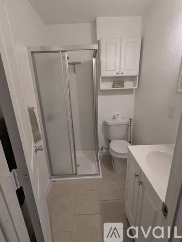 A small bathroom with a toilet, sink, and shower.