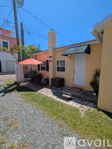 A yellow house with a white door and a red umbrella.