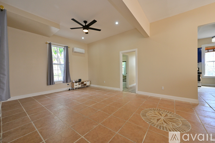 A spacious room with a ceiling fan and tiled flooring.