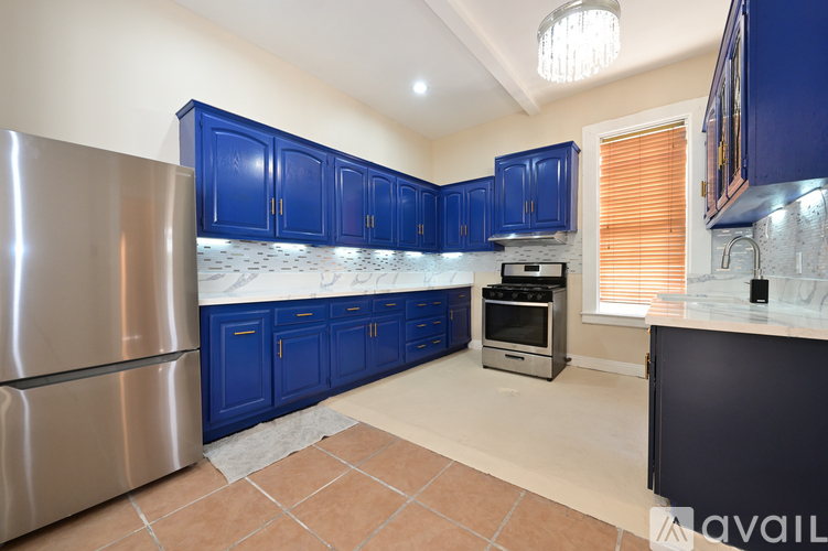 A kitchen with blue cabinets and a stainless steel refrigerator.