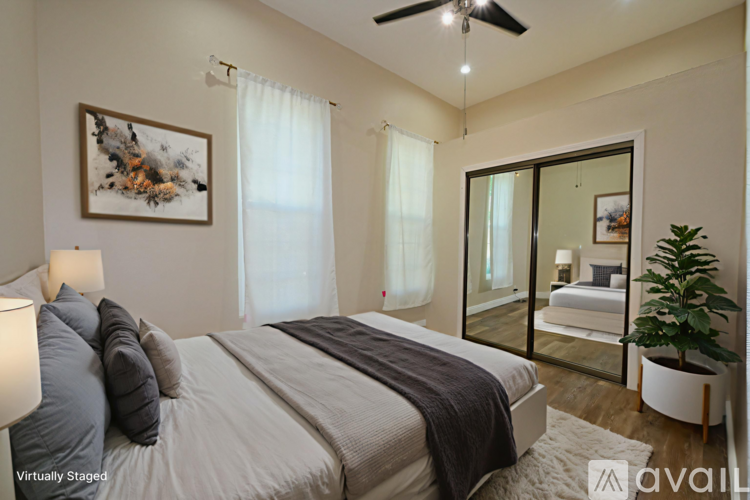 A bedroom with a large bed, a ceiling fan, and a painting on the wall.