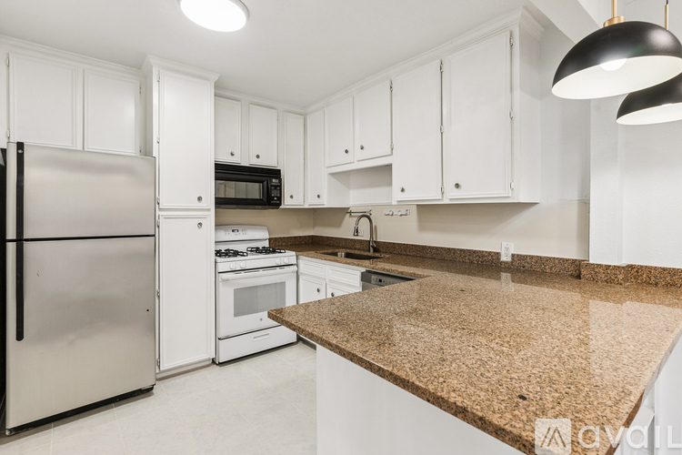 A kitchen with white cabinets and a granite countertop.