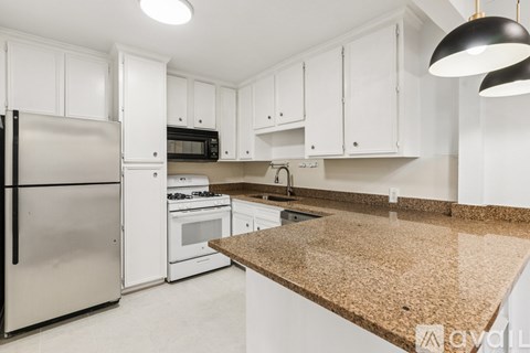 A kitchen with white cabinets and a granite countertop.